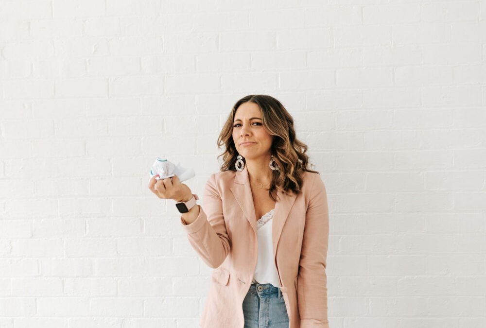 Woman in pink blazer holds crumpled paper