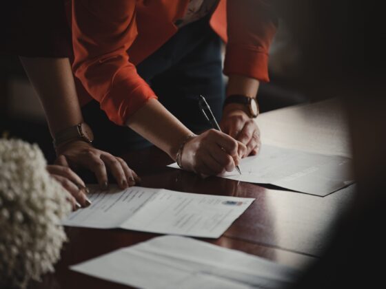 Person in orange sleeves signing a document