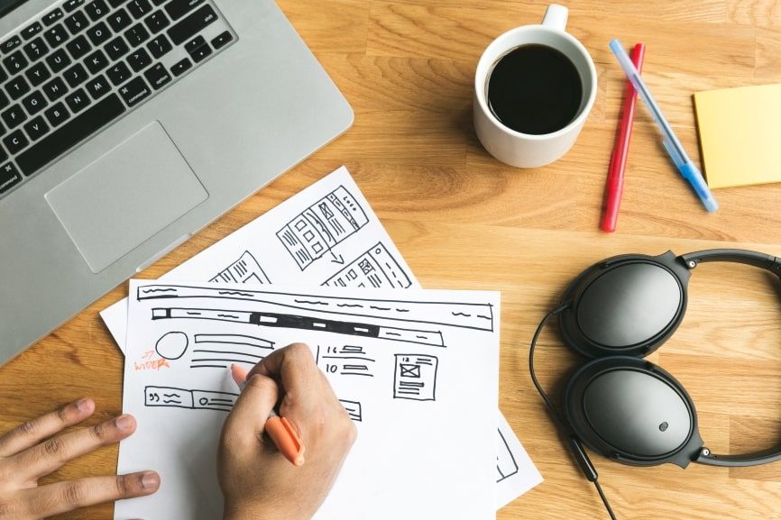 Close-up of hands sketching a document layout on a desk.